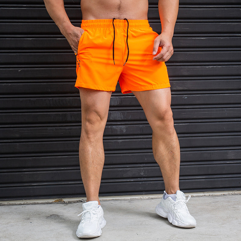 Person wearing bright orange shorts with a black background