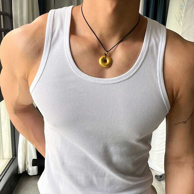 Person wearing a white tank top and a necklace with a gold pendant.