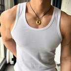Person wearing a white tank top and a necklace with a gold pendant.