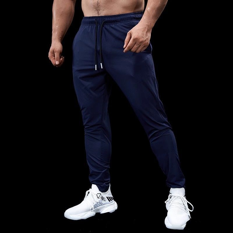 Person wearing navy jogger pants and white sneakers on a black background