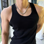 Person wearing a black tank top and silver chain necklace indoors.
