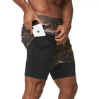 Person wearing camouflage shorts with a black pocket holding an iPhone.
