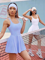 Two women in tennis attire on a tennis court with a blue wall.