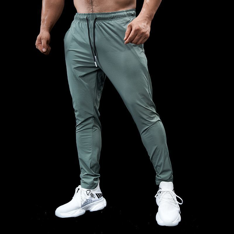 Person wearing green athletic pants and white sneakers on a black background