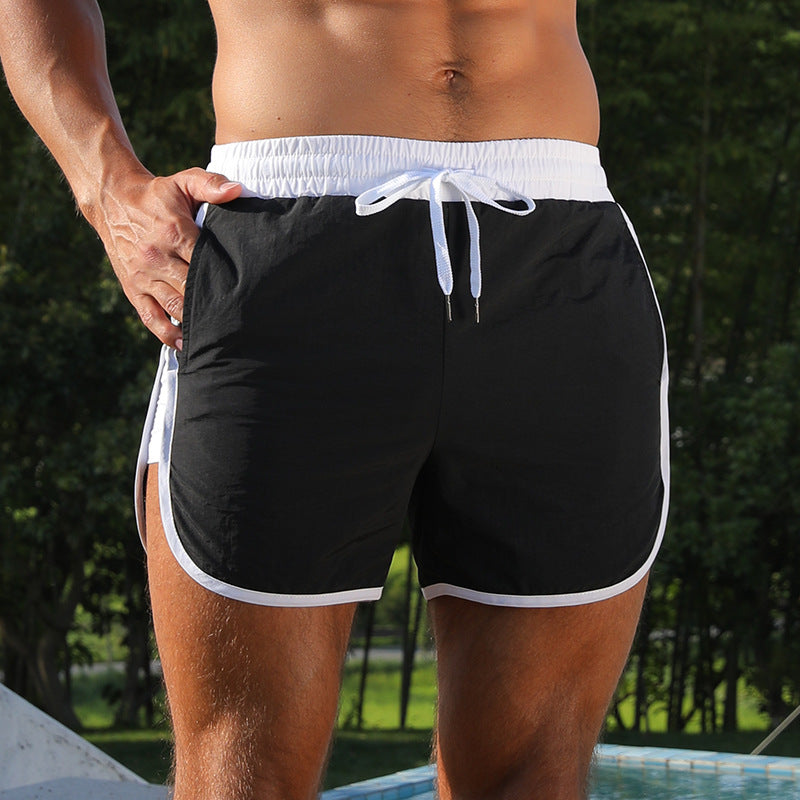 Person wearing black swim shorts with white trim in a natural setting