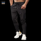 Person wearing black jogger pants and white sneakers on a black background