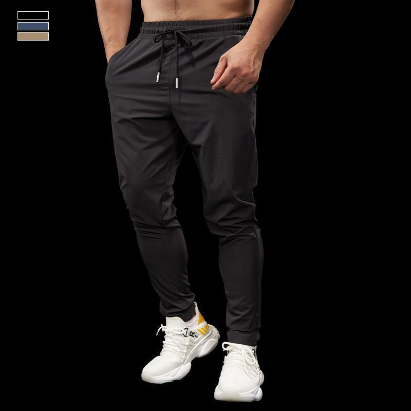 Person wearing black jogger pants and white sneakers on a black background