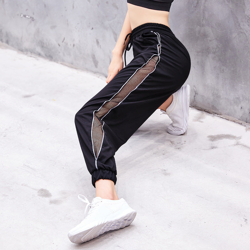 Person wearing black athletic pants with white stripes on a gray background