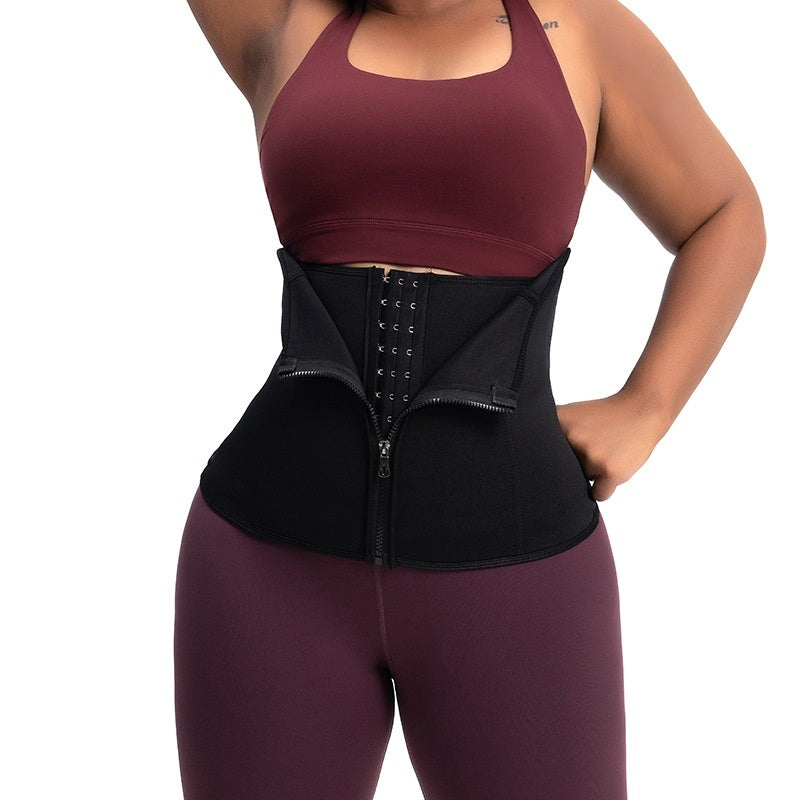 Person wearing a black waist trainer with maroon sports bra and leggings on a white background