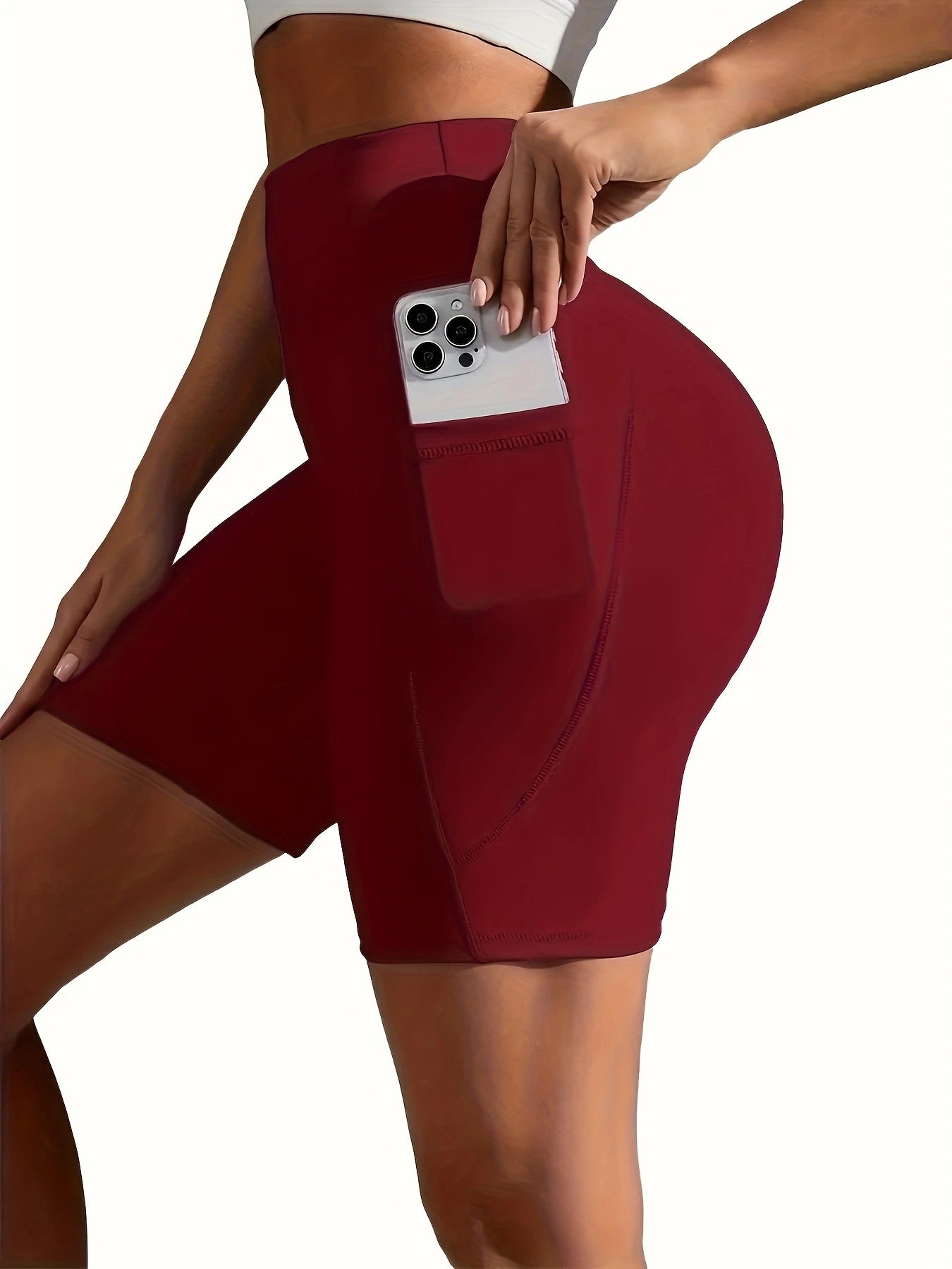 Maroon athletic shorts with a pocket held by a person on a white background