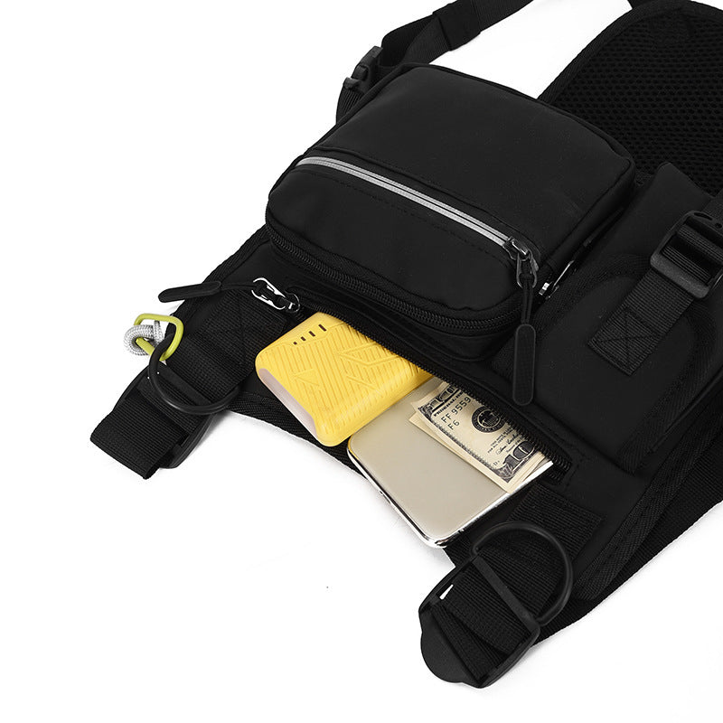 Black sling bag with compartments containing a yellow phone case and a silver wallet on a white background