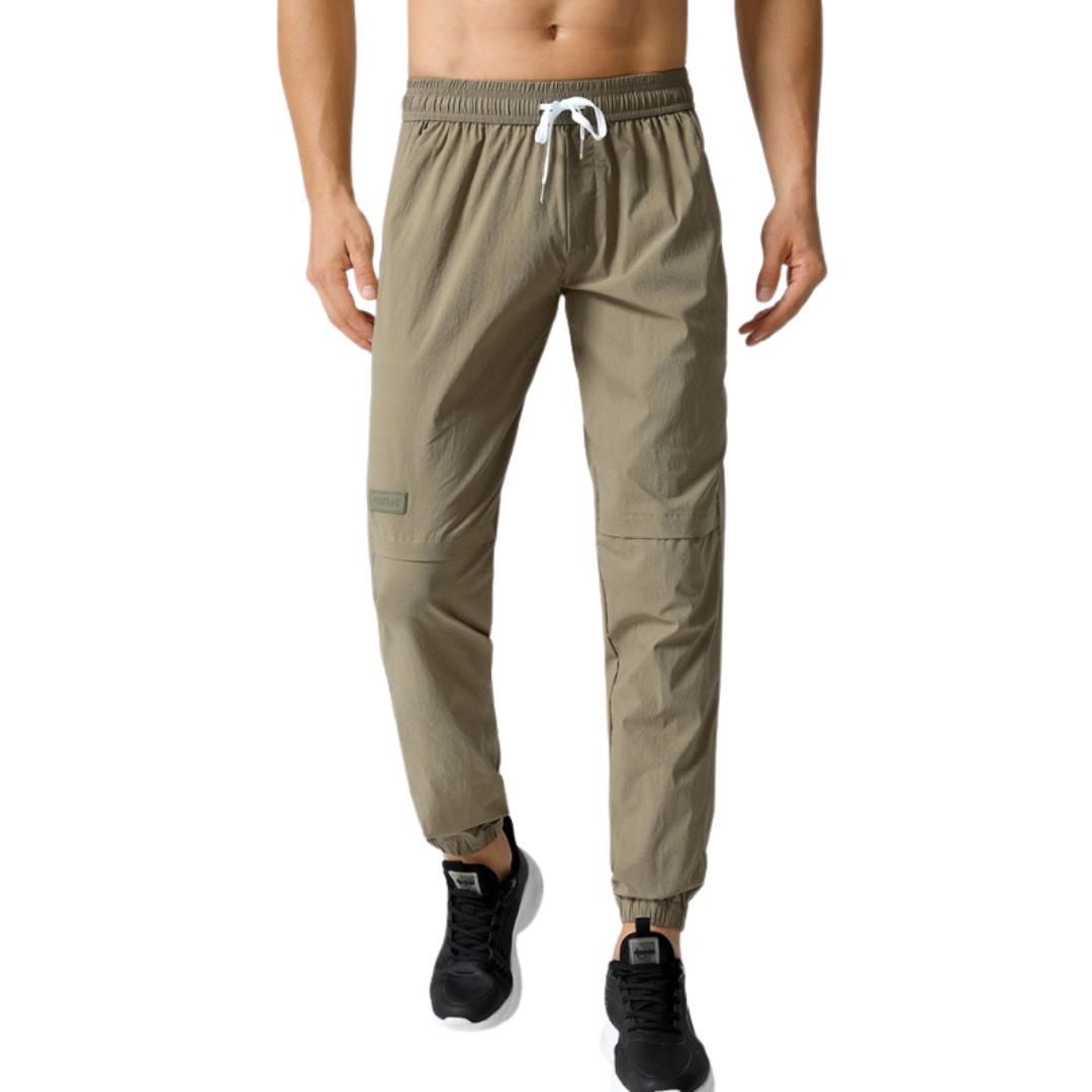 Beige jogger pants worn by a person on a white background
