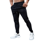 Black athletic pants worn by a person on a white background