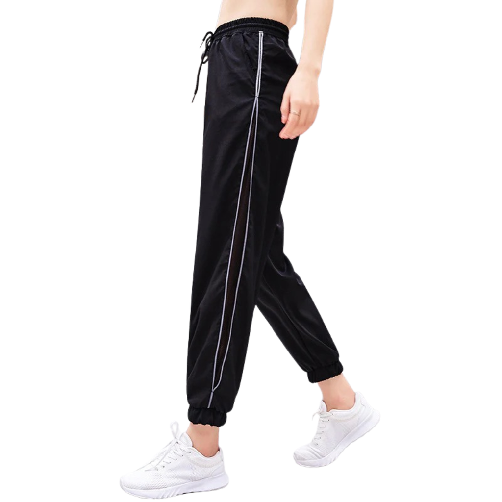 Black jogger pants with white stripes worn by a person on a white background