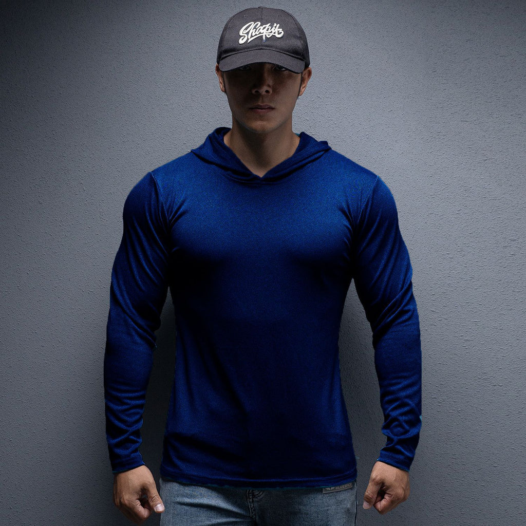 Person wearing a blue long-sleeve shirt and dark cap against a gray background