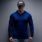 Person wearing a blue long-sleeve shirt and dark cap against a gray background