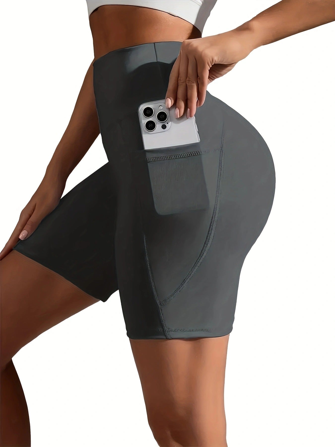 Person wearing gray athletic shorts with a pocket holding a phone on a white background