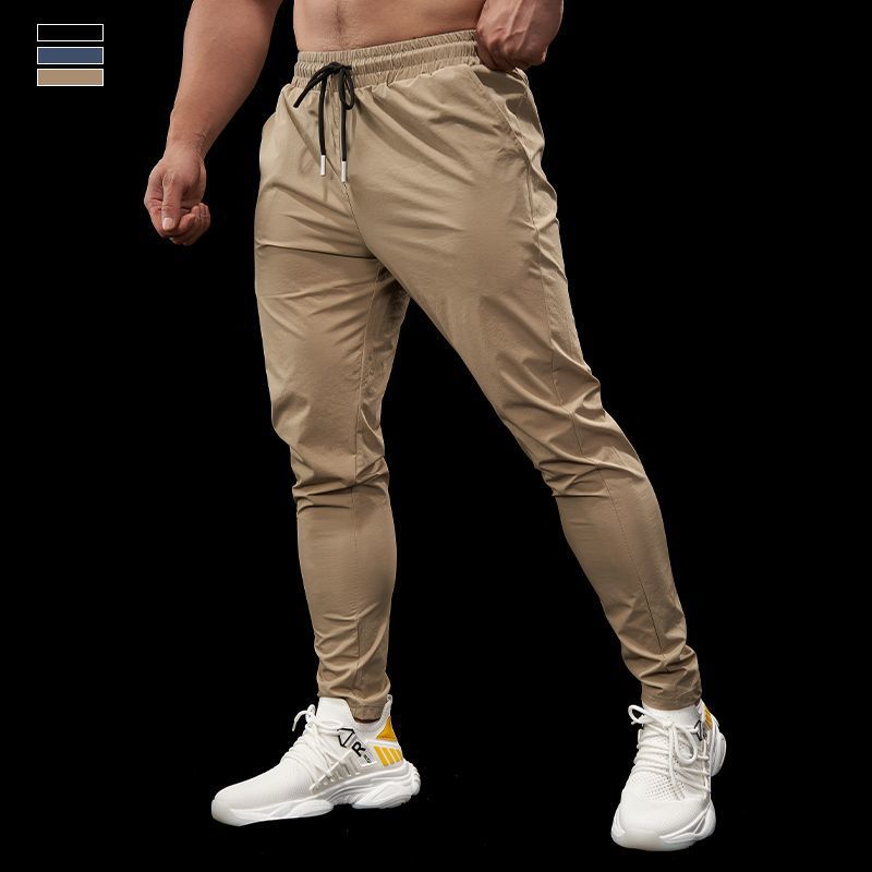 Beige jogger pants worn by a person on a black background